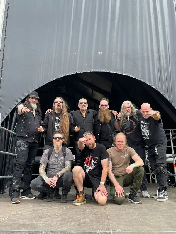 Merch crew posing in front of a festival stage tent